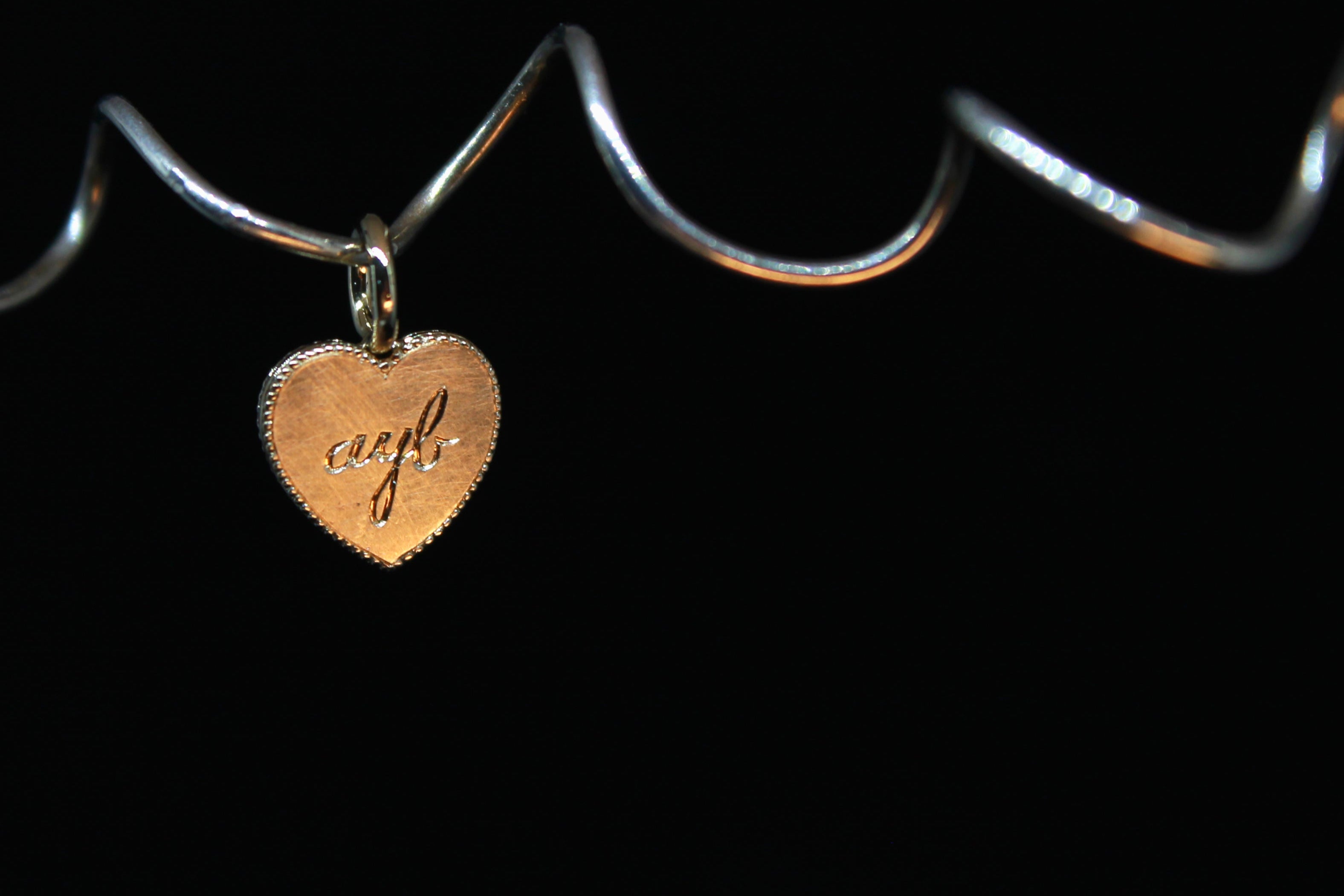 Heart-shaped charm with engraved text on a black background