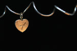 Load image into Gallery viewer, Heart-shaped charm with engraved text on a black background
