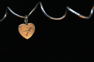Heart-shaped charm with engraved text on a black background